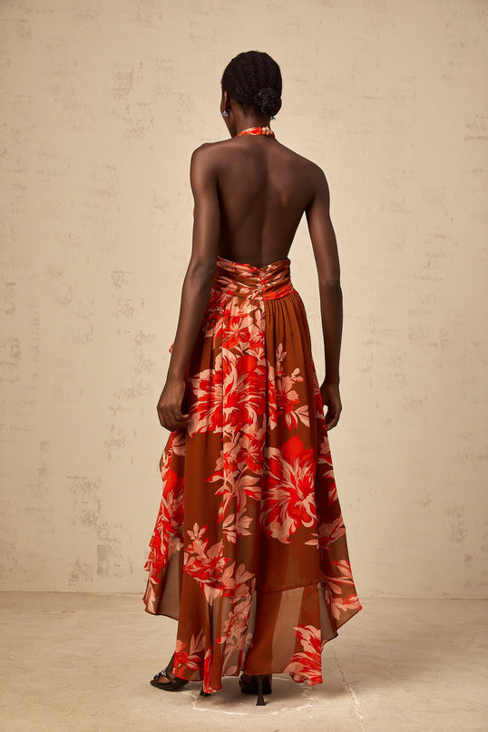 A long brown maxi dress with an asymmetrical hemline featuring a floral print pattern named Angelique