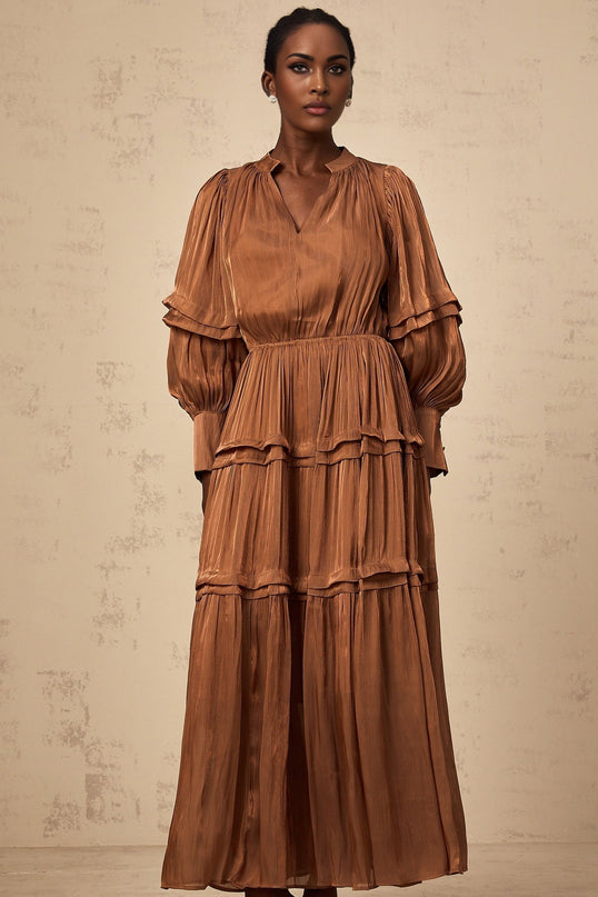 A long brown maxi dress with ruffled trim and tiered layers featuring a flowing silhouette and feminine design