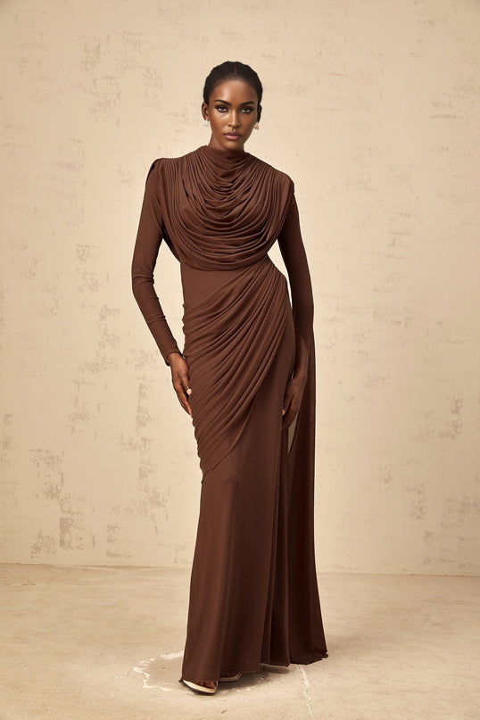 A long brown maxi dress with shirred detailing and draped fabric flowing to the floor
