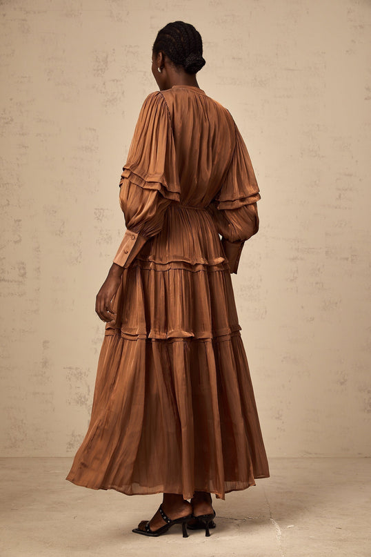 A long brown maxi dress with tiered layers and ruffled trim details