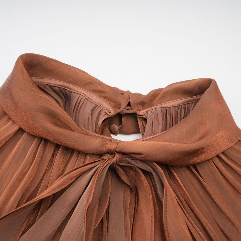 A long brown pleated satin maxi dress with a flowing silhouette