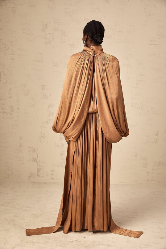 A long brown satin maxi dress with pleated details and a flowing silhouette