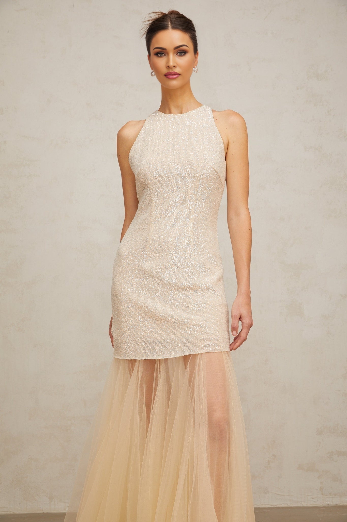 A long champagne colored maxi dress with sequin detailing and sheer tulle panels flowing to the floor
