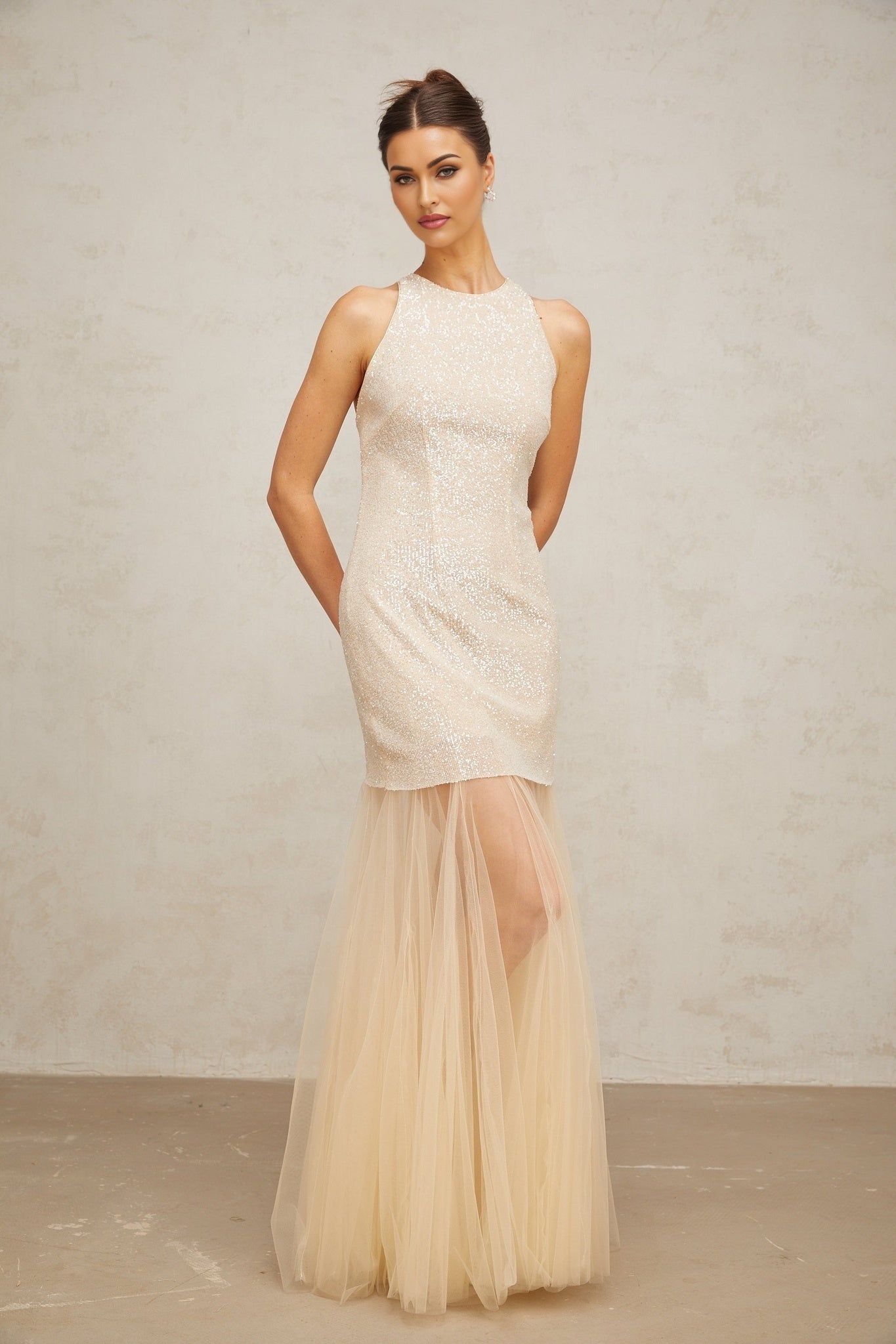 A long champagne colored maxi dress with sequin embellishments and sheer tulle panels