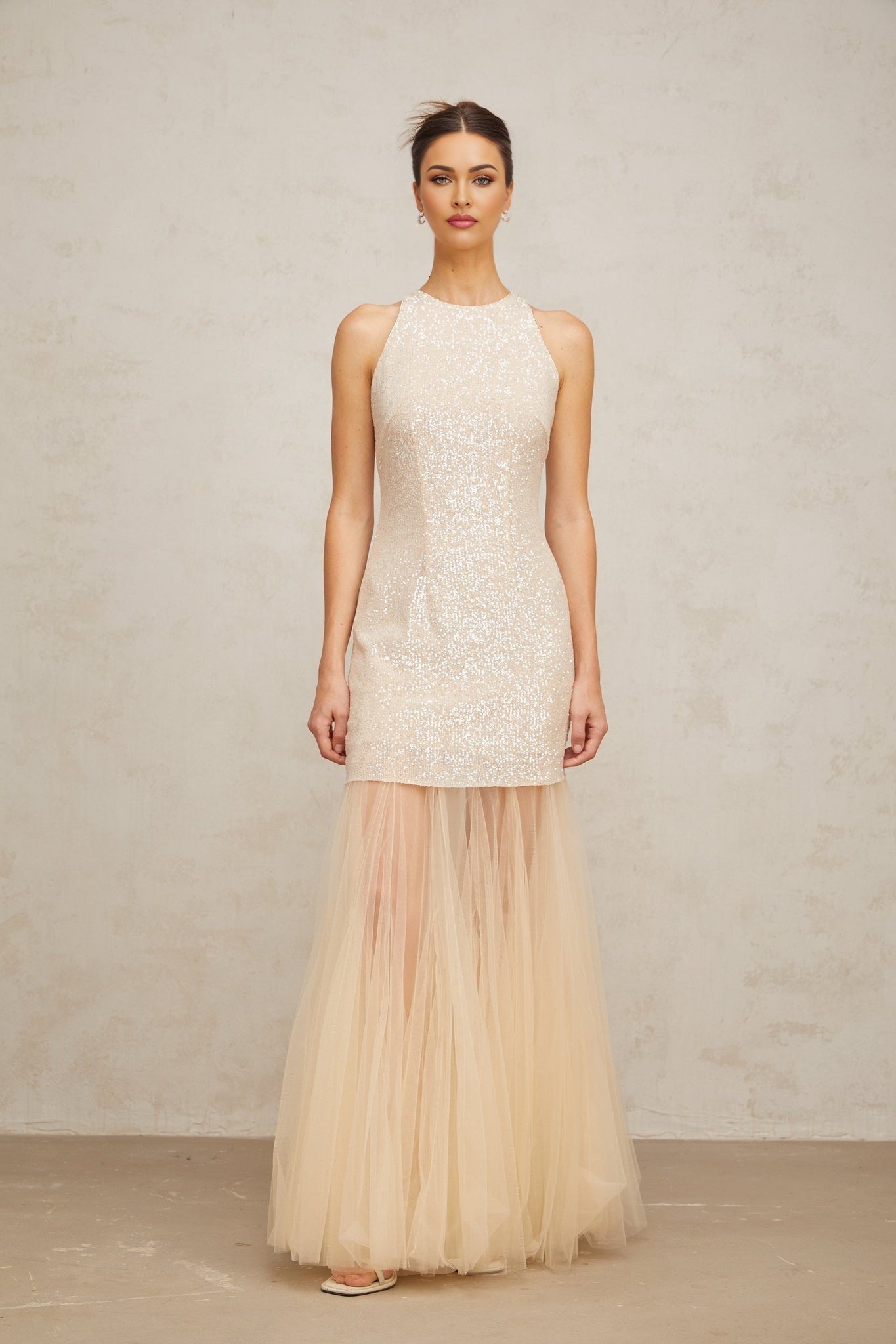 A long champagne colored maxi dress with sequin embellishments and sheer tulle panels