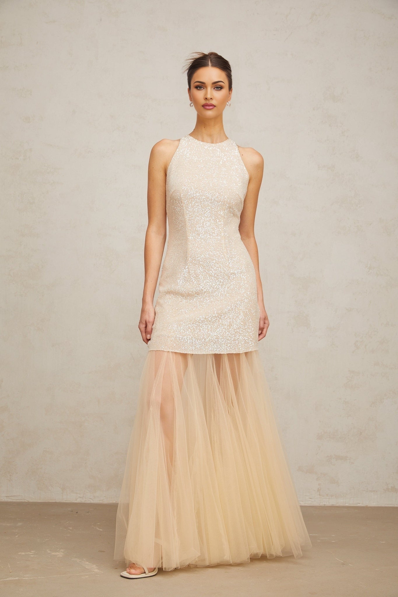 A long champagne colored maxi dress with sequin embellishments and sheer tulle panels