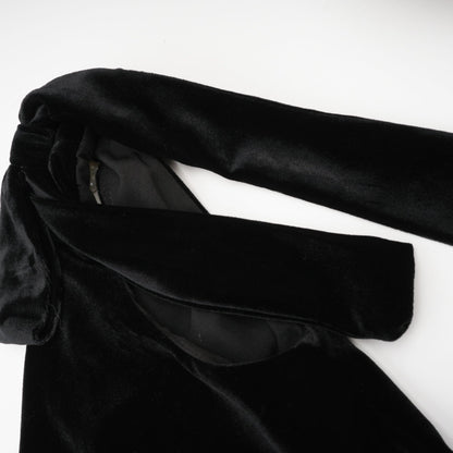 A long dark velvet dress with an open back and embellished details named Audrey shown on a model against a plain background