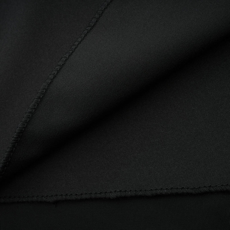 A long dark velvet dress with an open back and embellished details worn by a model standing in an elegant pose