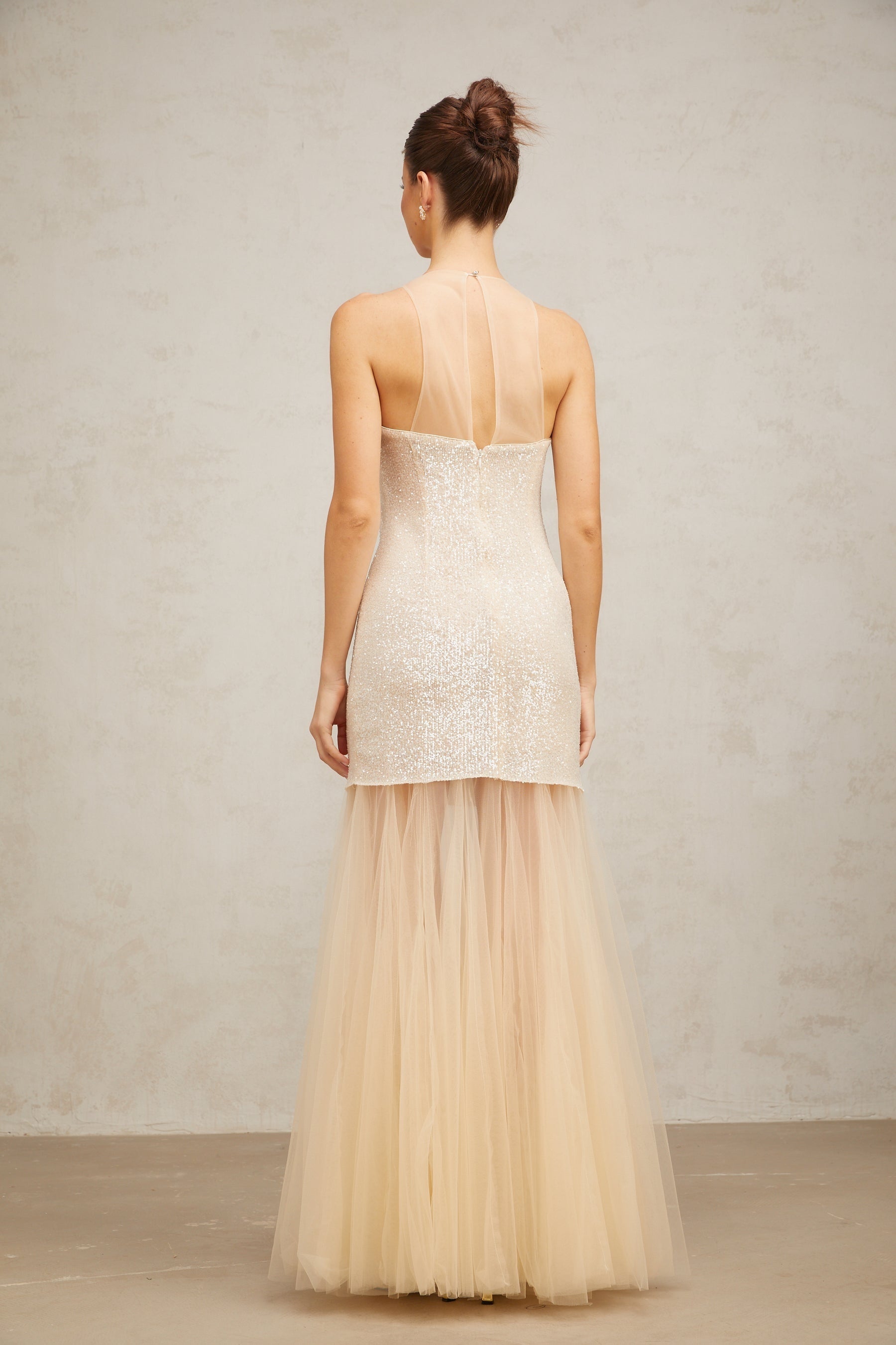 A long elegant champagne colored maxi dress with sequin detailing and sheer tulle panels