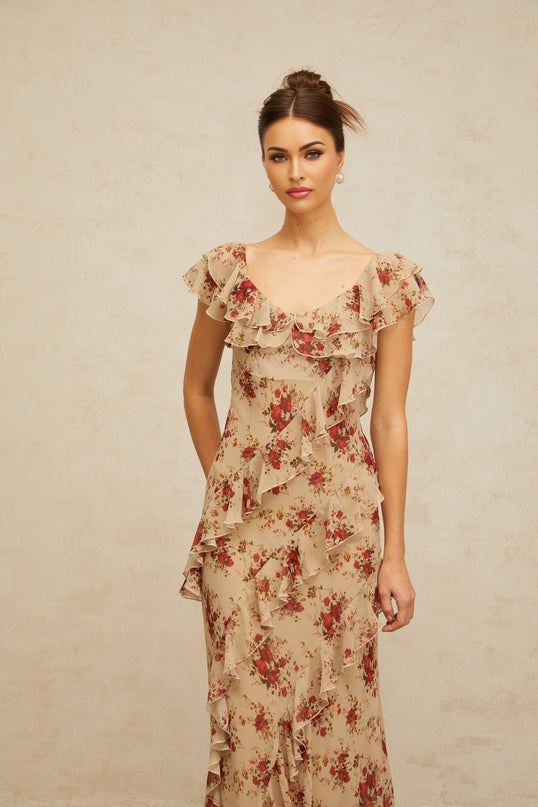 A long flared maxi dress with a floral print pattern and ruffled details shown on a model or hanging display