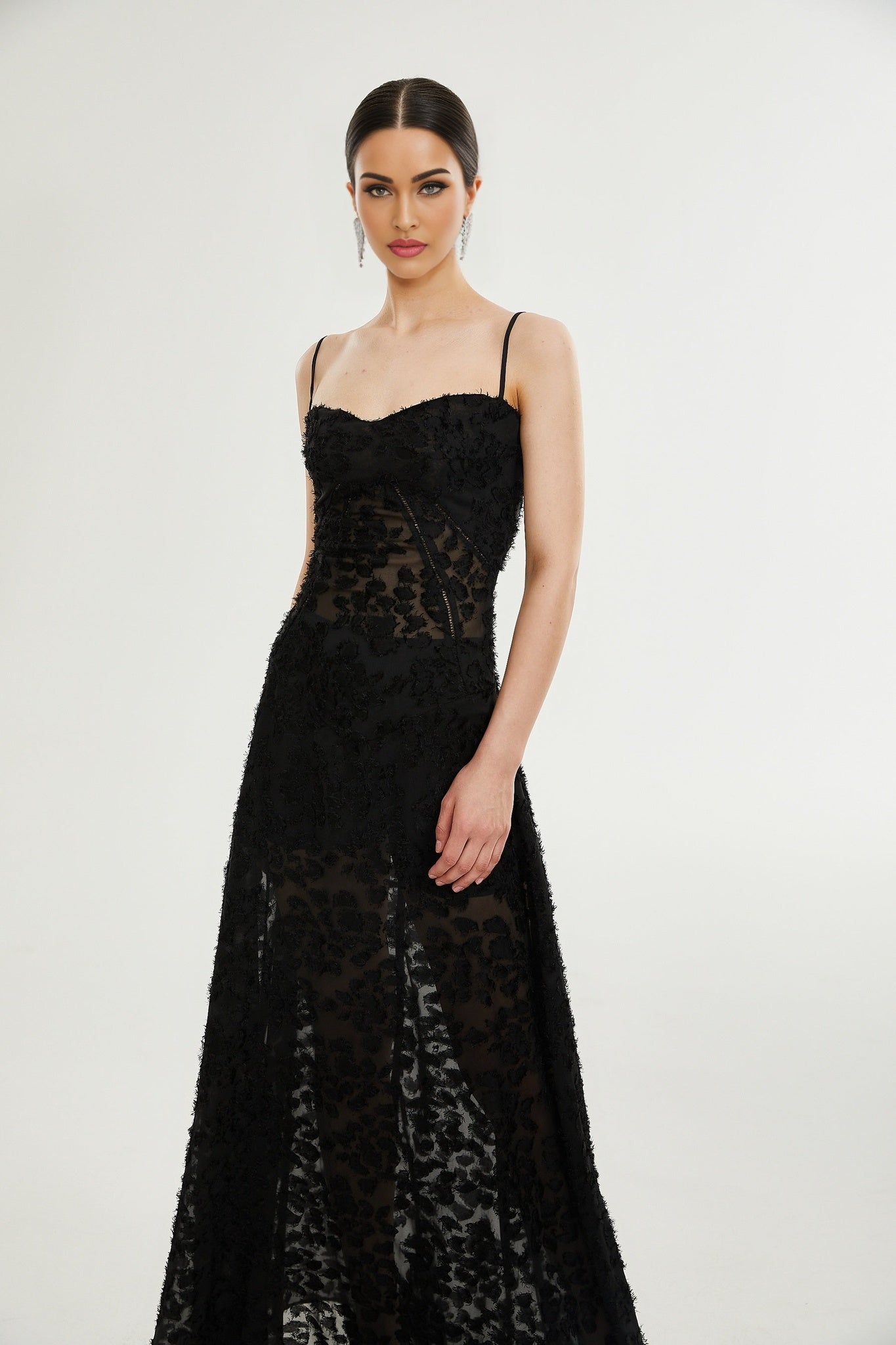 A long floral lace maxi dress in white with delicate floral patterns covering the entire garment featuring long sleeves and a floor length skirt