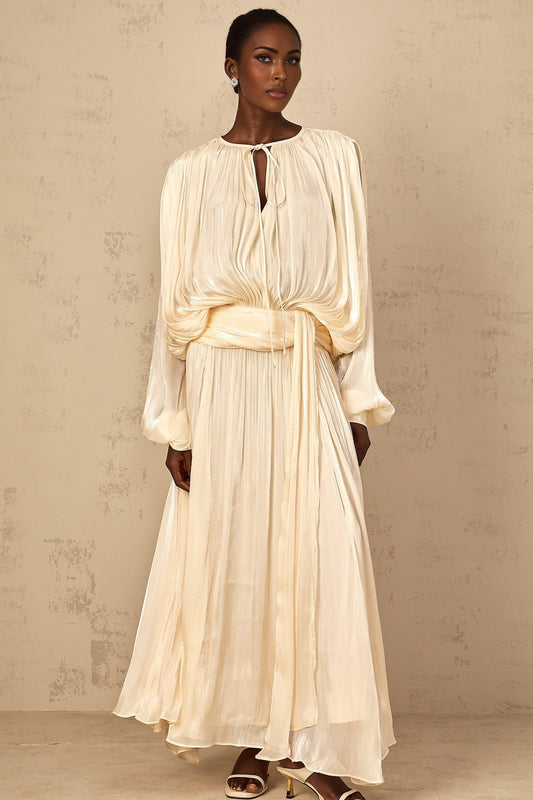 A long flowing maxi dress in a neutral color with pleated ruffles and a feminine silhouette named Eugenie