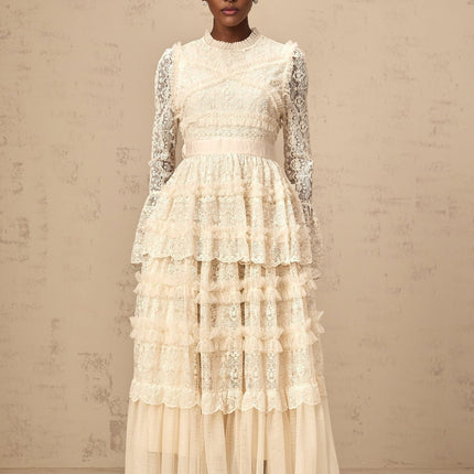 A long flowing maxi dress in neutral tones featuring lace panels and ruffled tulle details