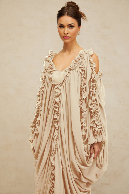 A long flowing maxi dress in tulle fabric with ruffled trim details and a feminine silhouette