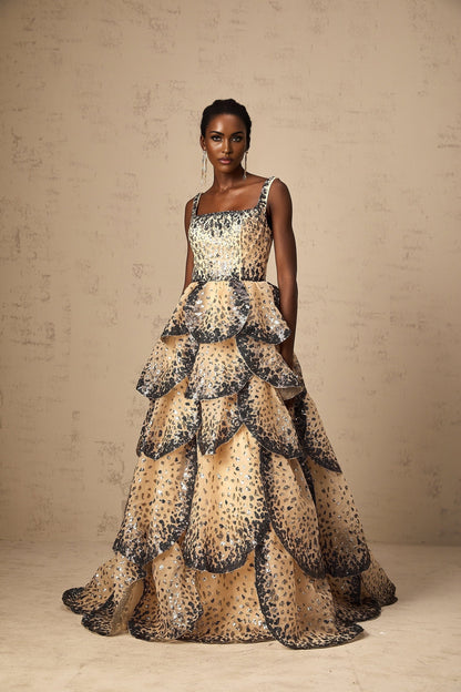 A long flowing maxi dress with tiered layers featuring sequined petal details throughout the fabric creating a shimmering effect