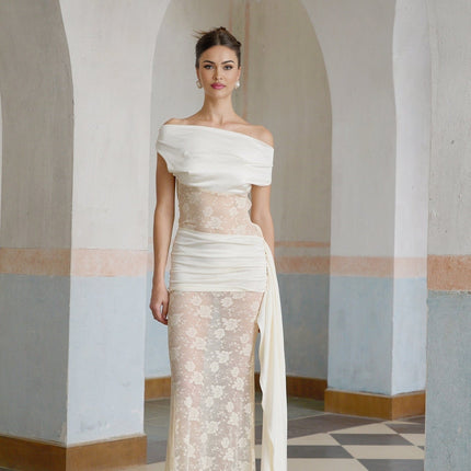 A long flowy maxi dress in neutral tones featuring floral lace panels and ribbon details with a feminine silhouette