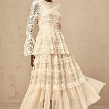 A long flowy maxi dress in neutral tones with lace panels and ruffle details made from tulle fabric