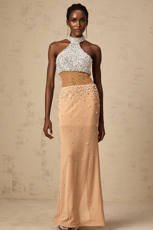 A long flowy white maxi dress with sheer fabric adorned with small pearllike embellishments scattered throughout the design