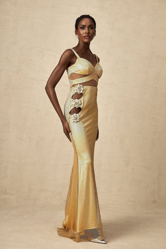 A long gold maxi dress with floral cutout patterns worn by a model standing against a plain background