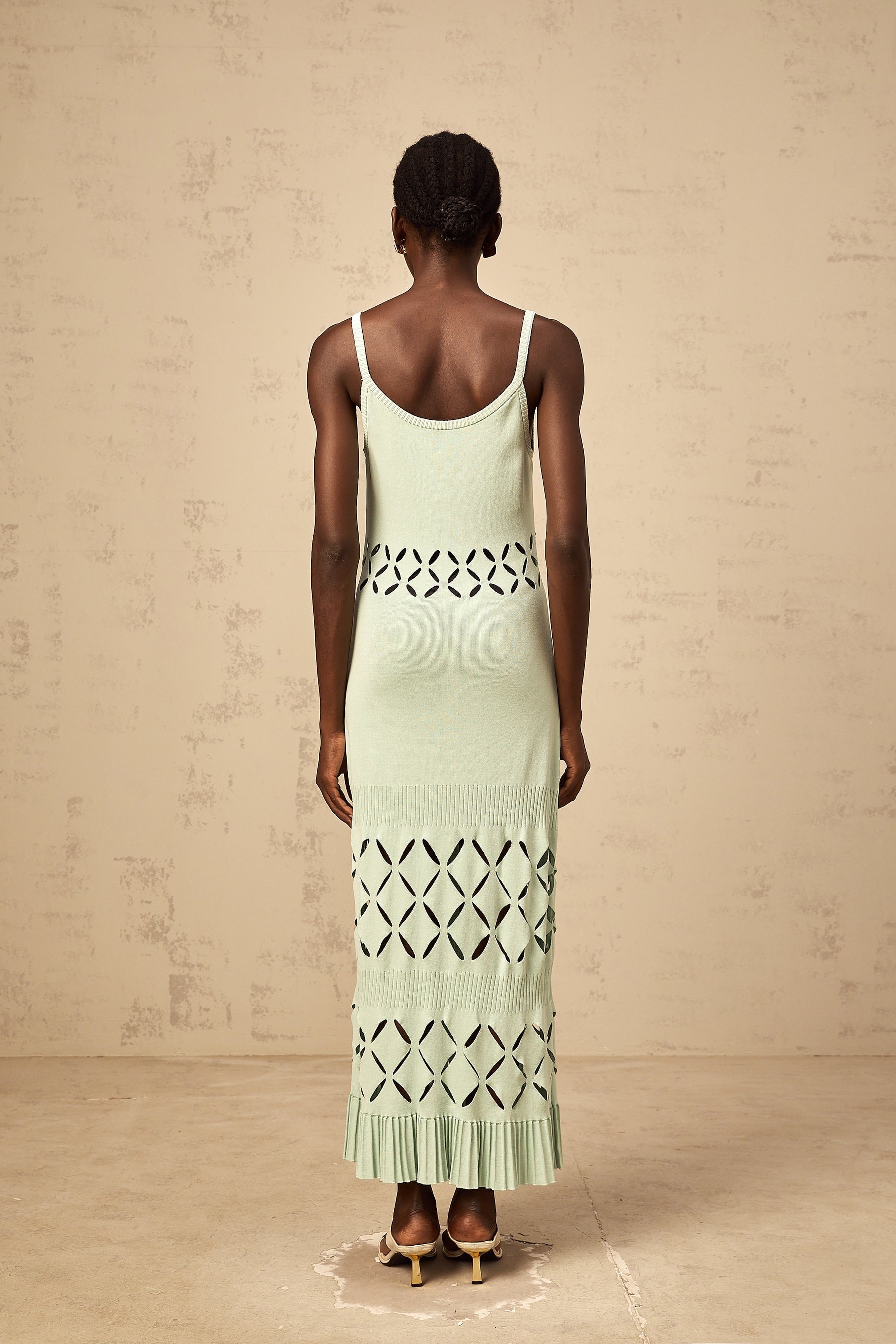 A long green knitted maxi dress with cutout details featuring a formfitting silhouette and a floorlength skirt