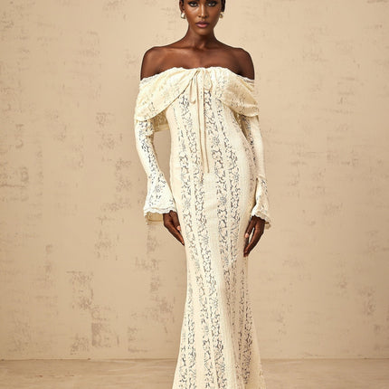 A long neutral colored maxi dress with floral lace detailing and a train design featuring delicate patterns and a flowing silhouette