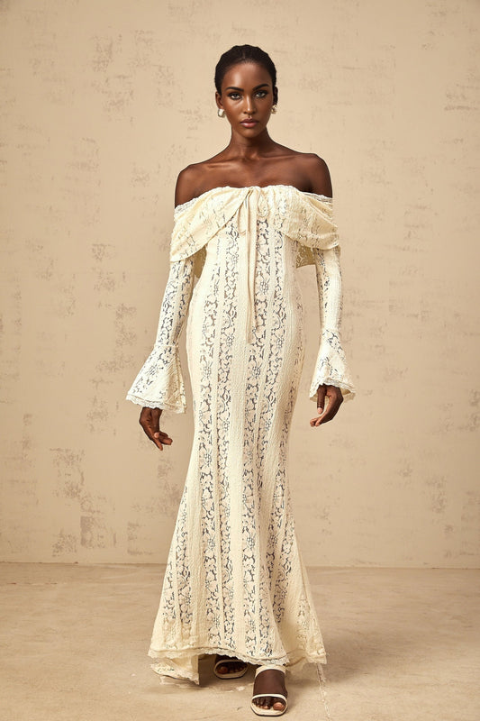 A long neutral colored maxi dress with floral lace details and a train design featuring delicate patterns and a flowing silhouette