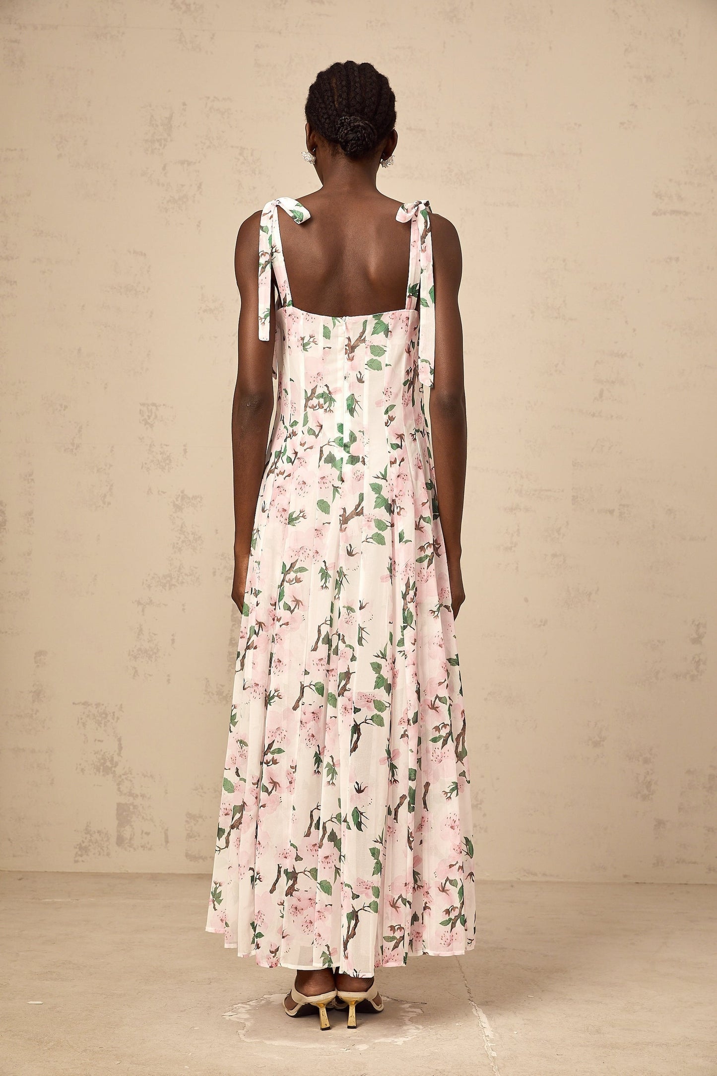 A long pink maxi dress with a floral print pattern and thin tied straps