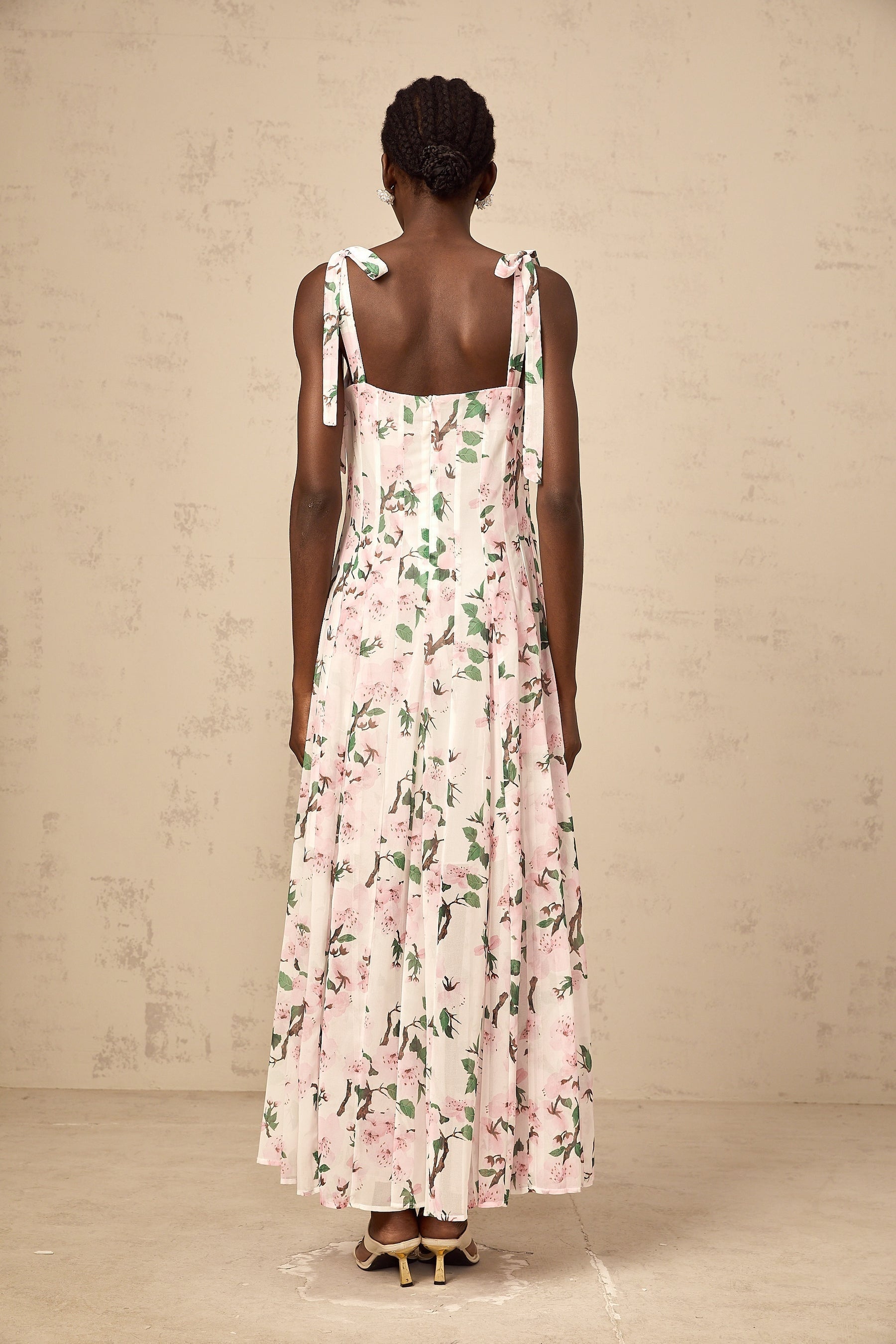 A long pink maxi dress with a floral print pattern and thin tied straps