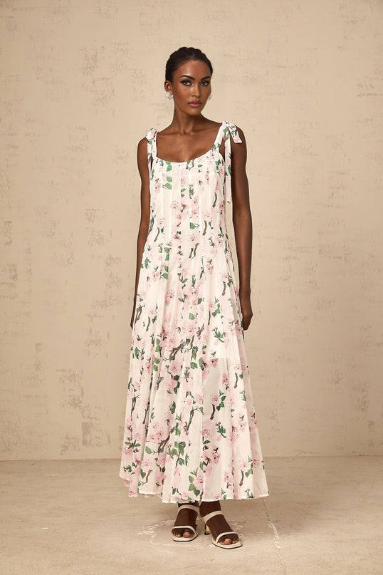 A long pink maxi dress with a floral print pattern and tied straps on the shoulders