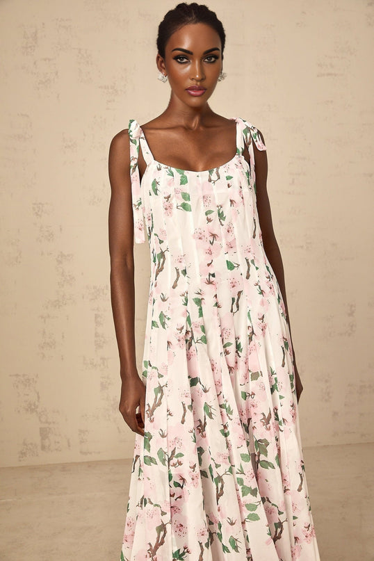 A long pink maxi dress with a floral print pattern and tied straps on the shoulders