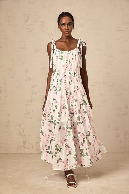 A long pink maxi dress with a floral print pattern and tied straps