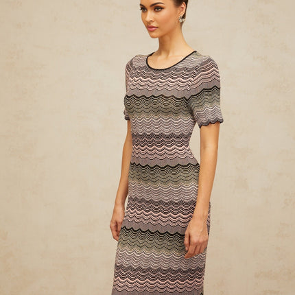 A long pink maxi dress with a wavy crochet knit pattern and a flowing silhouette