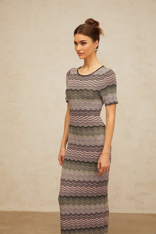 A long pink maxi dress with a wavy crochet knit pattern and a flowing silhouette