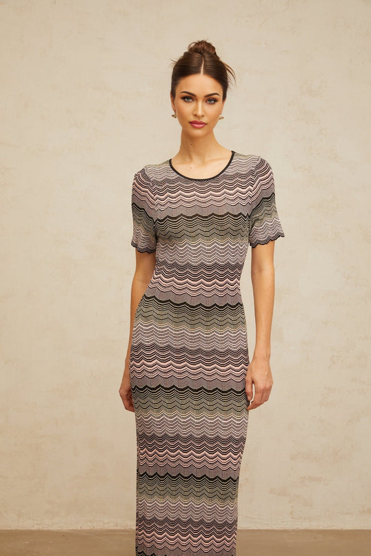 A long pink maxi dress with a wavy crochet knit pattern and a flowing silhouette