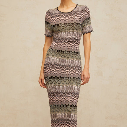 A long pink maxi dress with a wavy crochet knit pattern featuring a fitted bodice and flowing skirt