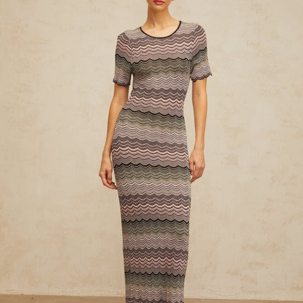 A long pink maxi dress with a wavy crochet knit pattern featuring a flowing silhouette and intricate texture throughout