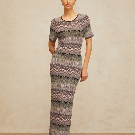 A long pink maxi dress with a wavy crochet knit pattern featuring a flowing skirt and fitted bodice