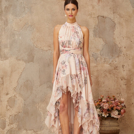 A long pink maxi dress with an asymmetrical hemline featuring a floral print pattern and a flowing design