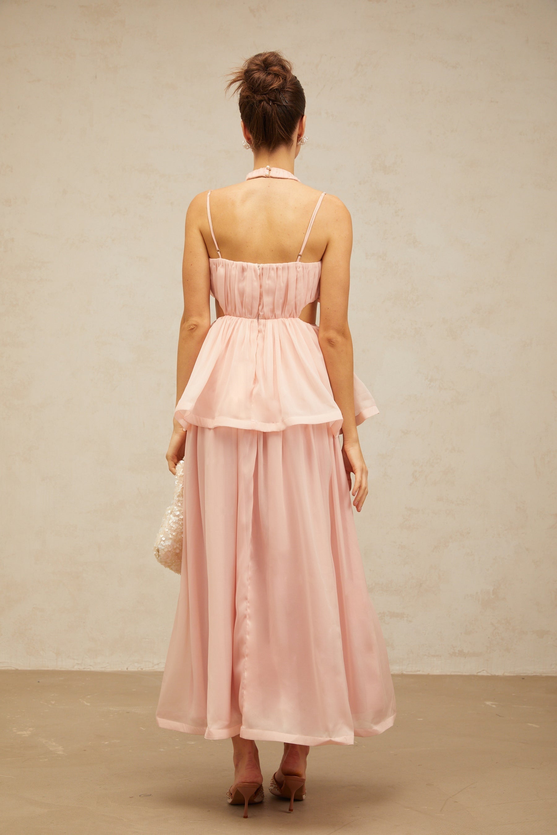 A long pink maxi dress with floral applique details and cutout sections featuring a flowy silhouette and romantic design