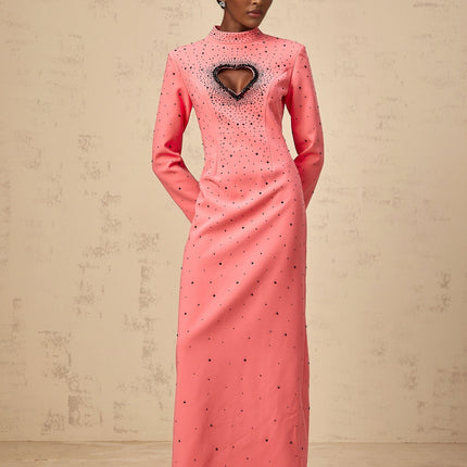 A long pink maxi dress with heart shaped cutouts and embellishments featuring a feminine silhouette and delicate details