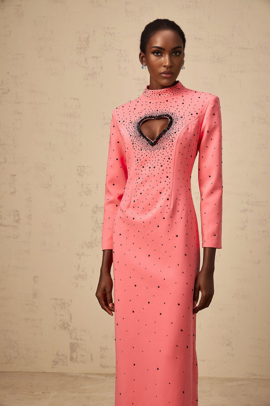A long pink maxi dress with heart shaped cutouts and embellishments featuring a feminine silhouette and romantic design