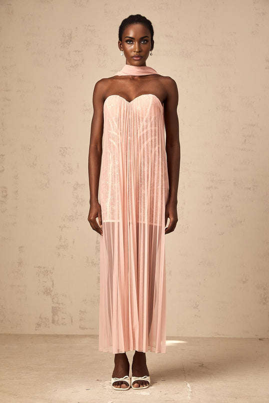 A long pink tulle maxi dress with pleats and ribbon details throughout the design