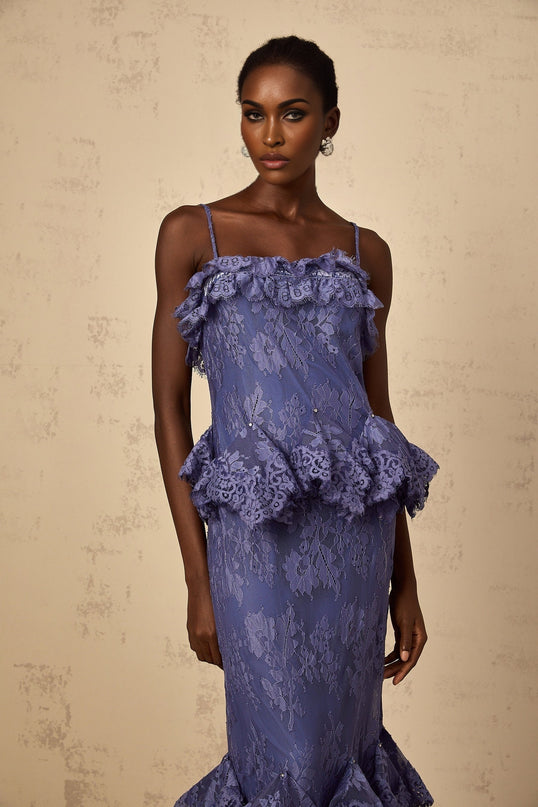A long purple maxi dress with floral lace details and ruffled accents worn by a model against a plain background