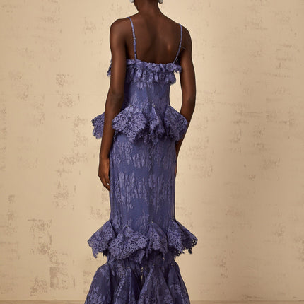 A long purple maxi dress with floral lace pattern and ruffled details shown on a model against a plain background
