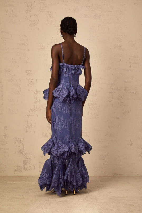 A long purple maxi dress with floral lace pattern and ruffled details shown on a model against a plain background