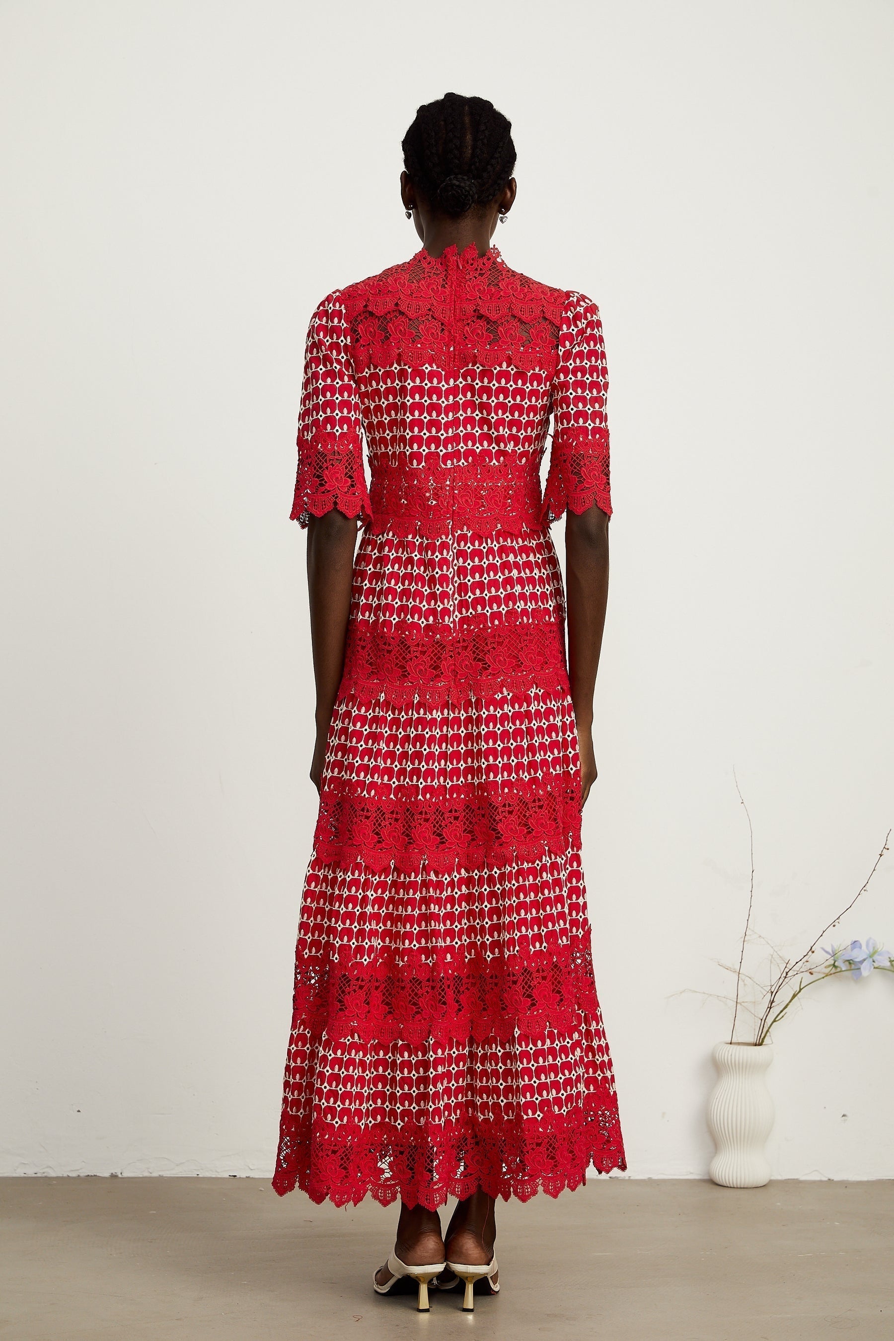A long red maxi dress with scalloped lace panels featuring a floral pattern