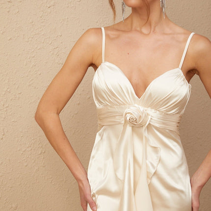 A long satin maxi dress in white with a corset bodice featuring colorful floral applique details and a flowing skirt