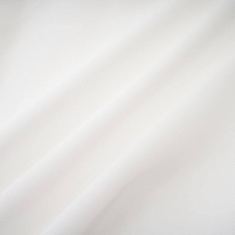 A long white chiffon maxi dress with a halter neck and ruffle details worn by a model against a plain background