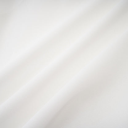 A long white chiffon maxi dress with a halter neck and ruffle details worn by a model against a plain background