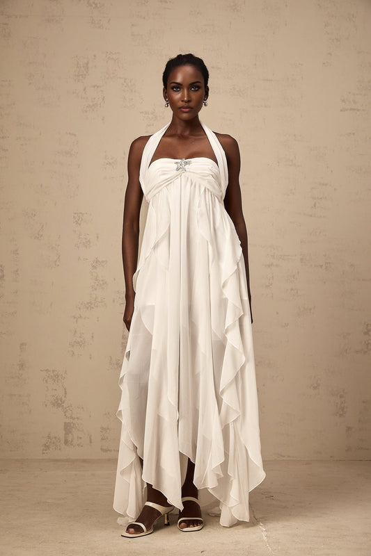 A long white chiffon maxi dress with a halter neck and ruffle details worn by a model against a plain background